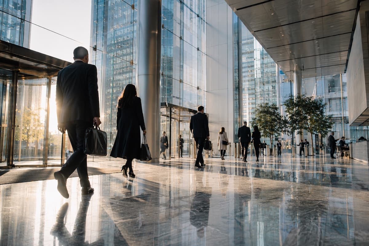 Professionals walking through a modern financial office lobby at golden hour