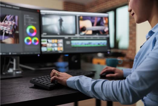 Professional video editor color grading footage on dual monitors